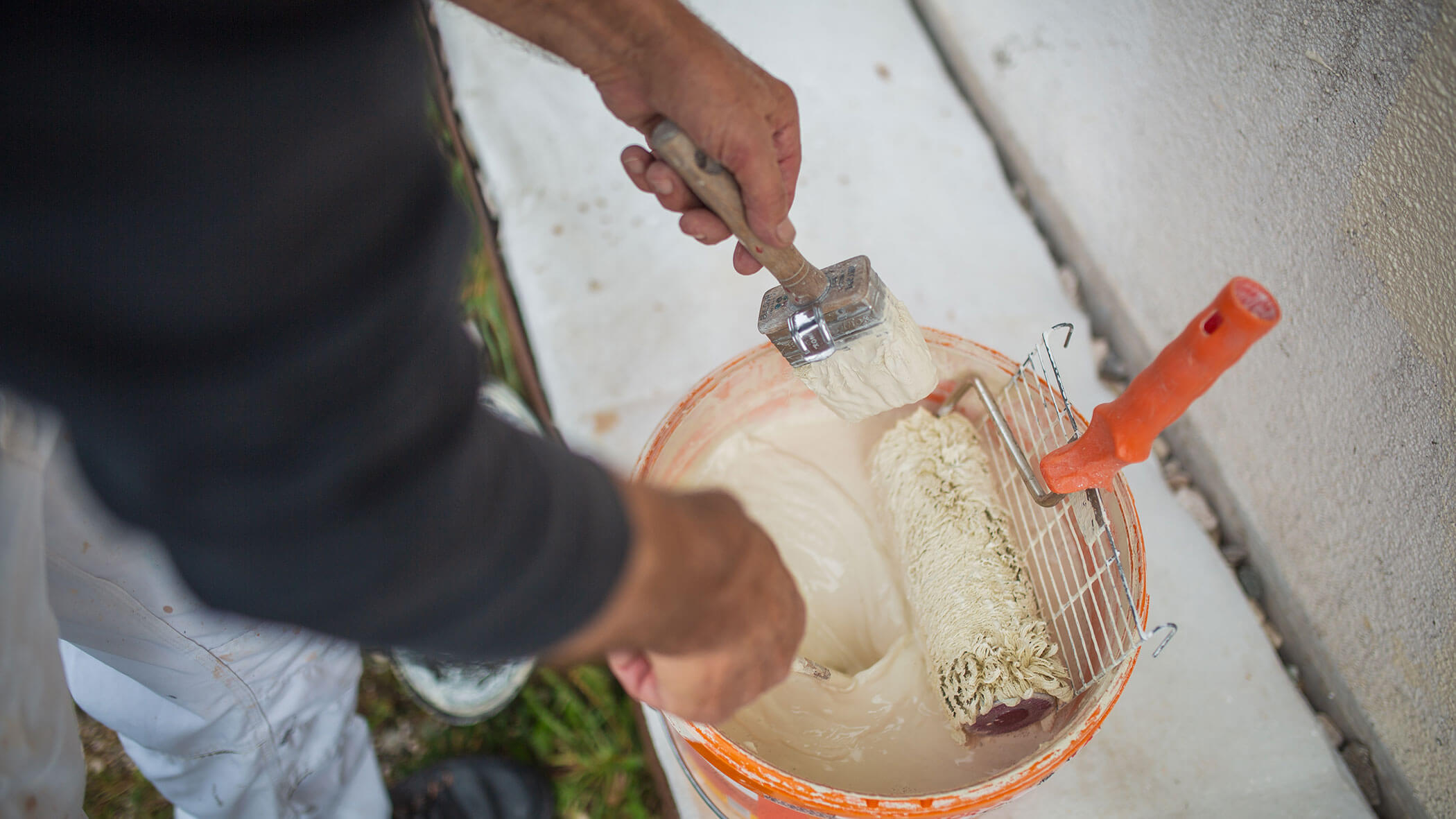 Arbeiter rührt Eimer mit Wandfarbe um - Ploner KG