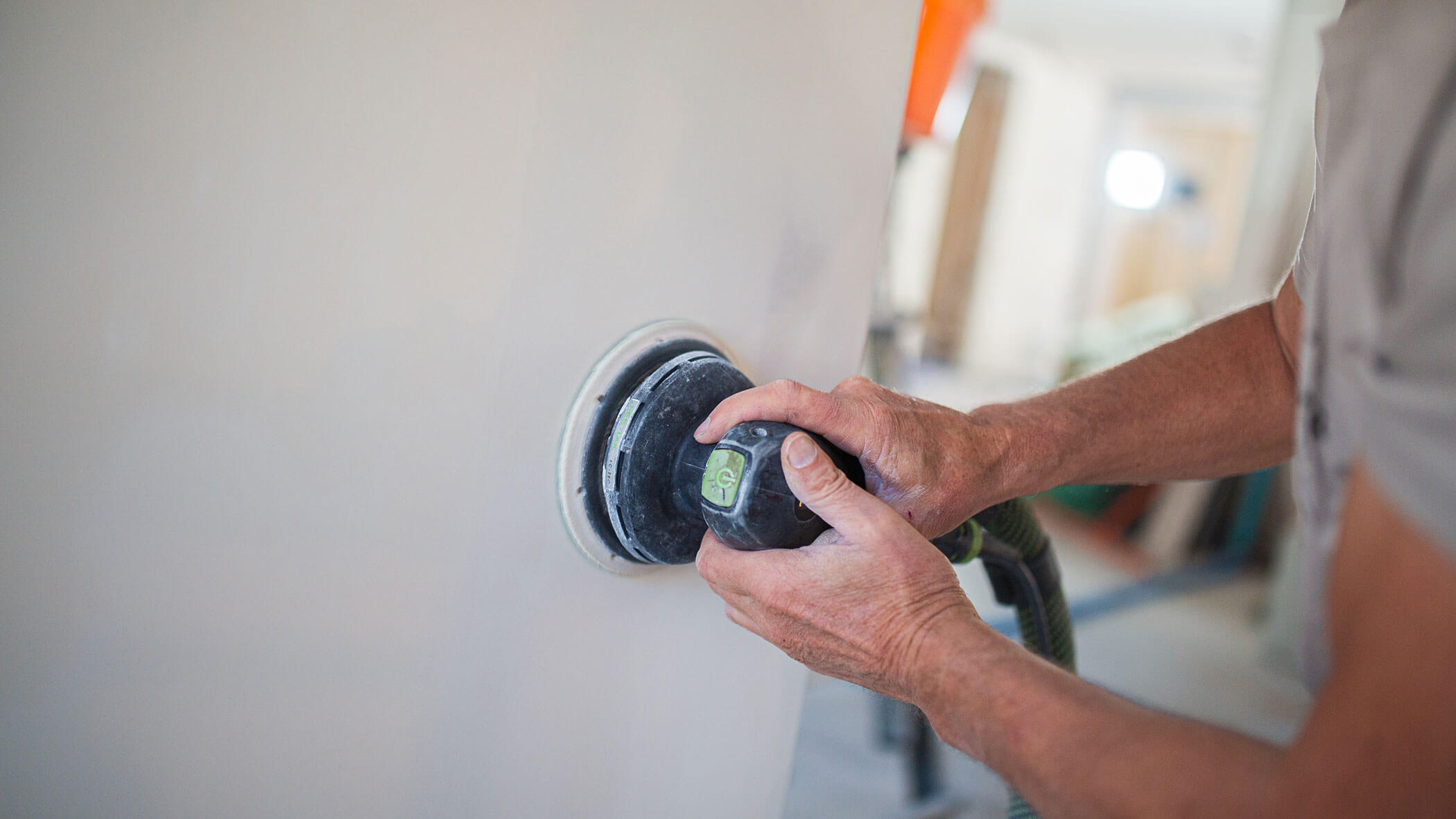 Mitarbeiter beim Abschleifen der Wand mit der Schleifmaschine - Ploner KG