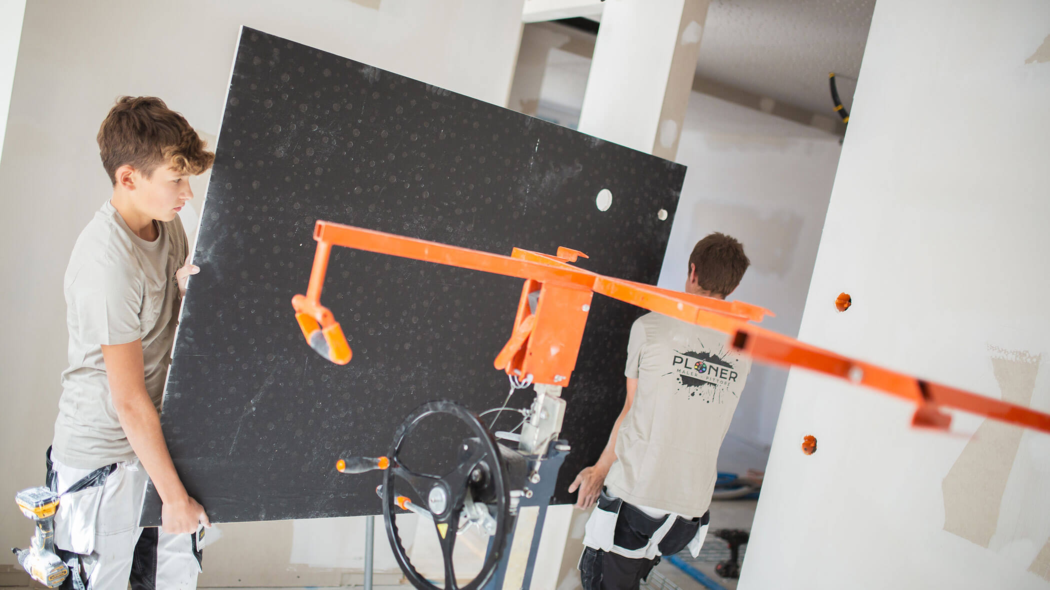 Zwei Mitarbeiter tragen eine schwarze Tafel - Ploner KG